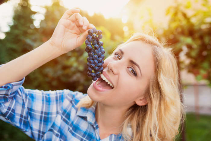 Woman eating a bunch of grapes