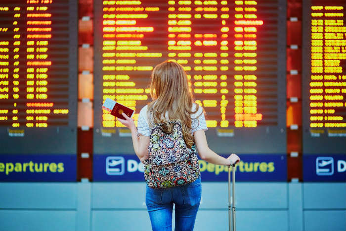 Woman At Airport Departure Board